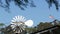 Classic retro windmill, bladed rotor and USA flag against blue sky. Vintage water pump wind turbine, power generator on livestock