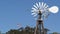 Classic retro windmill, bladed rotor and USA flag against blue sky. Vintage water pump wind turbine, power generator on livestock