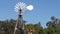 Classic retro windmill, bladed rotor and USA flag against blue sky. Vintage water pump wind turbine, power generator on livestock