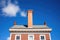 classic saltbox with white central chimney against deep blue sky