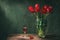 Classic still life with beautiful red tulip flowers bouquet in transparent glass vase and a glass of red wine. Art photography