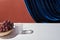 Classic still life with grape, glass on white table near velour curtain isolated on brown