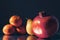 Classic still life image of mandarin, pear and pomegranate on a metal reflective surface. Dark background. Selective focus