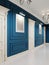 Classic-style corridor with blue walls and white doors and wood-paneled walls. The paintings on the walls