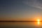 Classic sunset on a lake, with sun low on the horizon and flying