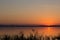 Classic sunset on a lake, with sun low on the horizon, flying bi