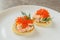 Classic Swedish appetizer - sandwiches with shrimps and caviar on white plate on dark table. Toast skagen ready to eat. Selective