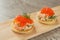 Classic Swedish appetizer - sandwiches with shrimps and caviar on wooden board on dark table. Toast skagen ready to eat. Selective