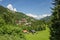 Classic swiss chalet in the middle of green alpine meadows . Cozy rural village Champery in Switzerland. Bright blue sky and white