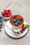 Classic tiramisu dessert with blueberries and raspberries in a glass and bowls with berries on concrete background