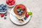 Classic tiramisu dessert with blueberries and raspberries in a glass and bowls with berries on concrete background