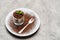 Classic tiramisu dessert in a glass on plate with fork silhouette on concrete background