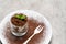 Classic tiramisu dessert in a glass on plate with fork silhouette on concrete background