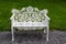 A classic white cast iron two-seater bench with oak leaf design throughout and attractive scrollwork on the seat, standing on a