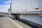 Classic white powerful big rig semi truck transporting cargo in dry van semi trailer with aerodynamic skirt running on the wide