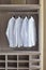 Classic white shirts in warm wooden wardrobe