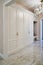Classic white wardrobe with seating in contemporary bright hallway. Carriage coupler closet bench