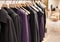 Classic women`s clothing on a hanger in a boutique. Purple and black tones in the collection. Jackets, coats, dresses