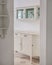 Classic wooden buffet cabinet for kitchenware in bright home interior. Storage furniture. View from hallway.