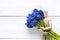 Classic wooden dummy holds blue muscari flowers on white wooden