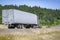 Classic work horse beige big rig semi truck transporting frozen cargo in reefer semi trailer driving on the scenic road with
