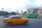 Classic yellow vintage Cuban car fast speeding with blurred background of yank tank tanks, bus & Capitol National at Havana, Cuba