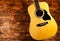 Classical acoustic guitar on a wooden background. Yellow stringed musical instrument for playing chords and melodies on