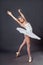 Classical Ballet dancer portrait. Beautiful graceful ballerina in white tutu from Swan lake practices releve ballet position in