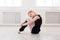 Classical ballet dancer stretching in white training class