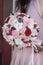 Classical bridal bouquet of preserved red rose and cotton flowers in hands. Bridal bouquet. Wedding bouquet of preserved