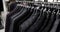 Classical different suit jackets on hangers in row in clothing shop in mall.