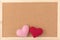 Classical plain brown cork board with red and pink knitting hearts at bottom of frame