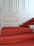 A classical staircase with a red carpet.