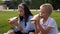 Classmates eat sandwiches together in the school yard sitting on the green grass