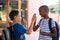 Classmates giving high-five at school corridor