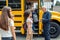 Classmates going into school bus while driver checking attendance concentrated joyful