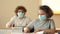 Classmates in protective medical masks, a boy and a girl are sitting at their desks at school. The boy asks the girl for