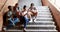 Classmates sitting on staircase and using mobile phone