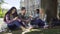 Classmates sitting under tree, girl touching guys arm, friendship and flirt