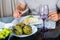 Classy dinner table setting, cooked artichokes sitting in middle, mans arms visible holding cutlery next to white plate