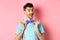 Classy handsome man fixing bow-tie on neck and smiling, getting ready for date or party, standing on pink background