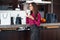 Classy young Latin woman drinking coffee standing in the kitchen relaxing after shopping