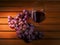 Claster of red grapes and glass of red wine on a wooden table surface. Concept wine making