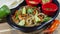 Clay dish with beef fajitas with pepper and onion strips accompanied by a plate of corn tortillas and spicy sauce, guacamole and a