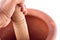 Clay mortar and wood pestle is used to mix the ingredient with male hand on white background cooking kitchenware object isolated