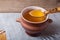 Clay pot with ghee and spoon on linen napkin. Rustic still life.