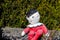 A clay statue of humpty dumpty sitting on a wall with a black hat and a red onesie