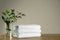 Clean bath towels and vase with green plants on table. Space for text