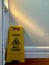 Clean Caution Wet Floor sign is behind the door. Vertical photo image.
