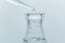 Clean clear water drop in to glass flask in blue medical research science laboratory background